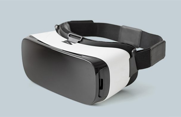 A VR headset sits on a table with a grey background.